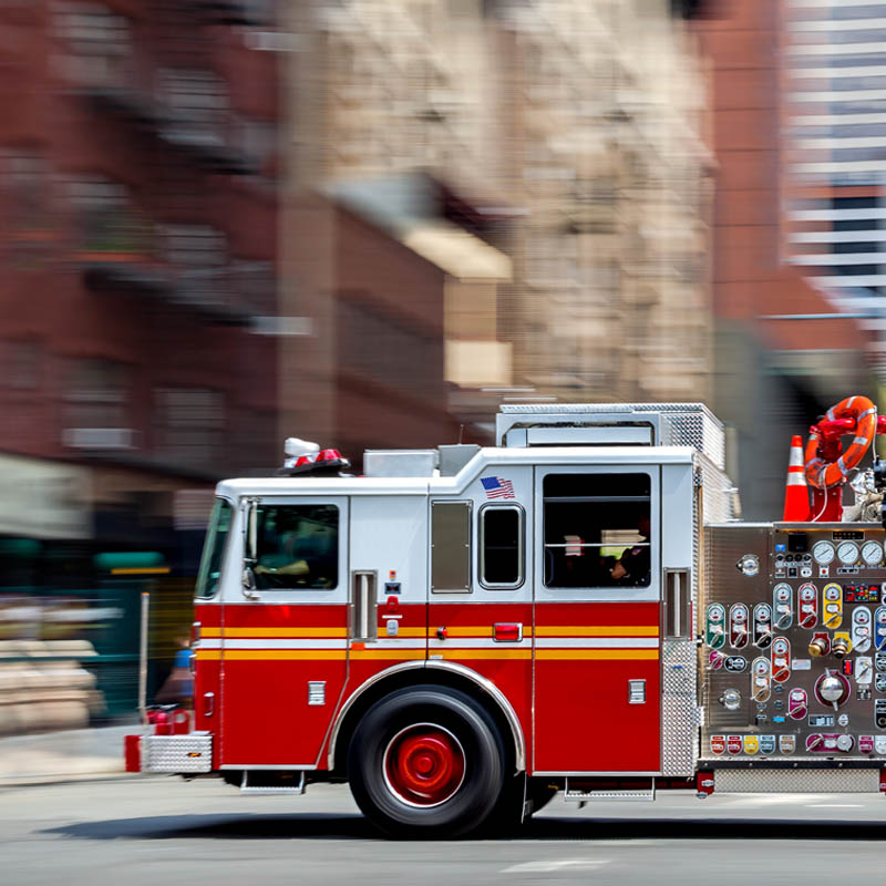 A fire truck driving quickly down a city street.